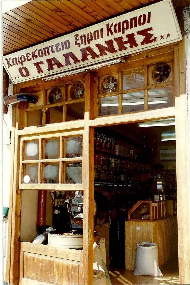 Η έγχρωμη πρόσοψη του παλιού καταστήματος στην Αρεθούσης 33, με τη ζωγραφιστή ταμπέλα «Καφεκοπτείο Ξηροί Καρποί Ο ΓΑΛΑΝΗΣ» και το καβουρδιστήρι στη βιτρίνα.